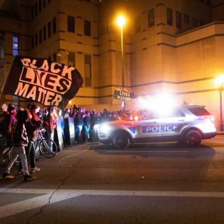 抗議者は夜にコロンバスの警官の車に近づく