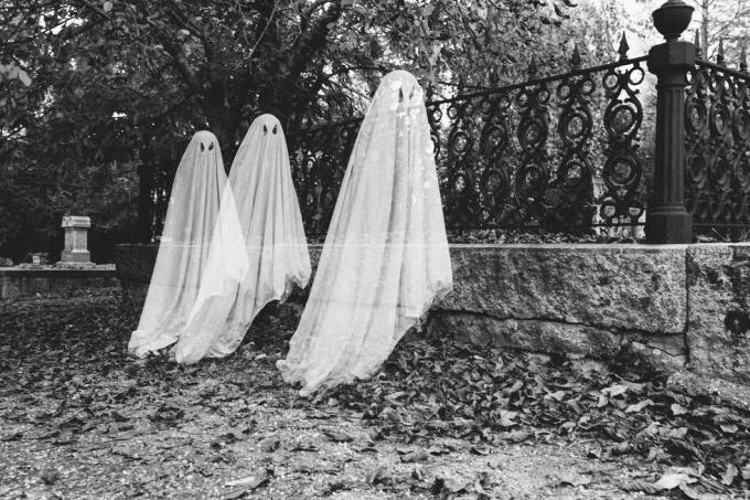 doble exposición de niños disfrazados de fantasmas en el cementerio durante halloween