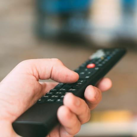 mão masculina segurando o controle remoto da televisão, fechar com foco seletivo