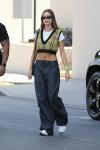 Hailey Bieber ma na sobie krótką kamizelkę w żółtą kratę i spodnie cargo