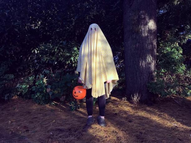 tonårspojke som bär en spökdräkt för halloween