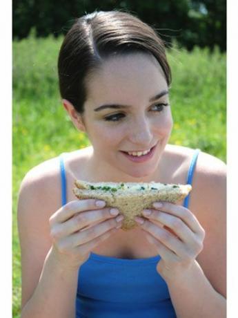 잔디에 앉아 샌드위치를 ​​먹는 소녀