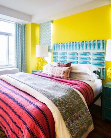 quarto com paredes amarelas e roupa de cama rosa