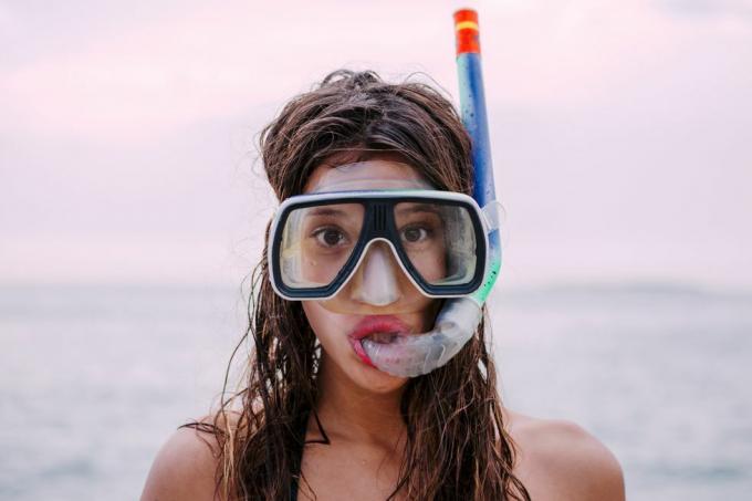 młoda kobieta z goglami do nurkowania i fajką ciągnąc śmieszne miny