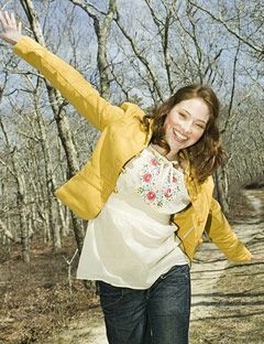 ragazza che corre con le braccia aperte e sorride